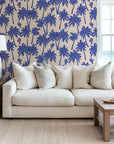 Blue palm wallpaper used as a living room accent wall, bringing a resort style feel with repeating palm trees and birds.