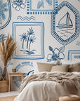 Nautical toile wallpaper installed in a bedroom, featuring sailboats, palm trees, and ocean icons that evoke a classic coastal atmosphere.
