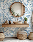 Coastal themed wallpaper used on a bathroom room accent wall, showcasing hand illustrated beach scenes and maritime details in blue and white.