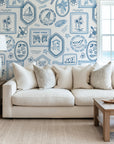 Ocean inspired toile wallpaper styled in a living room, adding timeless coastal charm with framed nautical illustrations and tropical motifs.