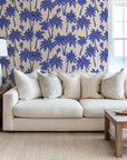 Blue palm wallpaper used as a living room accent wall, bringing a resort style feel with repeating palm trees and birds.