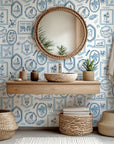 Coastal themed wallpaper used on a bathroom room accent wall, showcasing hand illustrated beach scenes and maritime details in blue and white.