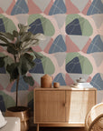 Non-representational wallpaper featuring overlapping, organic forms; the color scheme includes soft gray, dusty pink, deep navy, and sage, accented by thin crisscrossing lines