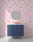 A dreamy night sky scene with golden lunar shapes and sparkling stars on rose-colored removable wallpaper - Celestial Blush