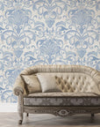 Dusky Garden Waltz removable wallpaper with blue damask scrolls on cream, styled behind tufted vintage sofa