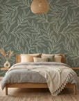 Sage green and cream Forest Leaf botanical wallpaper on bedroom accent wall with natural wood furnishings