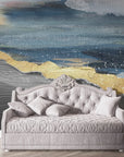 Landscape Gold abstract mural wallpaper with blue ocean waves and golden accents behind elegant daybed
