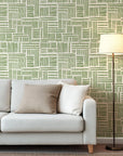 Abstract design showing manually drawn brush stroke sections in olive green that create a loose grid structure on a warm, off-white background.