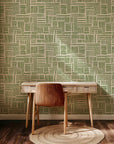 Decorative wallpaper showing an irregular geometric configuration of hand-drawn, thick brushstroke blocks in an olive hue, contrasting with the creamy beige base