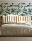 Arcadian Reverie Hunter pastoral toile wallpaper behind a channel-tufted bed in a calm primary bedroom
