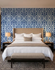 Aztec Quilt Indigo geometric tribal wallpaper behind the headboard of a king bed in a contemporary hotel guest room