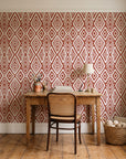 Aztec Quilt Terracotta geometric tribal wallpaper behind a vintage writing desk in a cozy craft-room home office