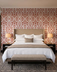 Aztec Quilt Terracotta geometric tribal wallpaper behind the headboard of a king bed in a contemporary hotel guest room