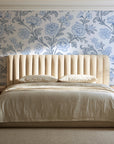 Blush Serenade Delft floral damask wallpaper behind a channel-tufted bed in a calm primary bedroom
