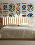 Bohemian Daisy Cream retro floral wallpaper behind a channel-tufted bed in a calm primary bedroom