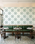 Captain's Wheel Evergreen nautical ship wheel wallpaper above a green leather banquette in a sunlit neighborhood cafe