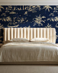 Coastal Village Midnight palm toile wallpaper behind a channel-tufted bed in a calm primary bedroom