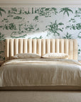 Coastal Village Sage palm toile wallpaper behind a channel-tufted bed in a calm primary bedroom