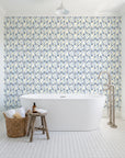 Crossroads Indigo geometric wallpaper behind a freestanding tub in a bright coastal bathroom