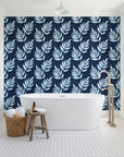 Driftwood Fern Midnight fern frond wallpaper behind a freestanding tub in a bright coastal bathroom