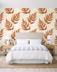 Driftwood Fern Terracotta fern frond wallpaper behind a queen bed in a bright coastal bedroom