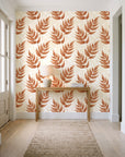 Driftwood Fern Terracotta fern frond wallpaper behind a console table in a light entry hallway
