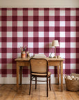 Dune Plaid Oxblood gingham check wallpaper behind a vintage writing desk in a cozy craft-room home office