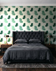 Dust & Wing Emerald butterflies wallpaper behind a tufted headboard in a dark, moody bedroom