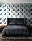 Dust & Wing Navy butterflies wallpaper behind a tufted headboard in a dark, moody bedroom