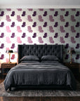 Dust & Wing Plum butterflies wallpaper behind a tufted headboard in a dark, moody bedroom