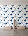 Ember & Leaf Midnight botanical floral wallpaper behind a travertine pedestal and vase in a minimal boutique