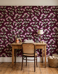 Evening Garden Oxblood botanical floral wallpaper behind a vintage writing desk in a cozy craft-room home office
