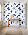 Falling Softly Navy botanical leaf wallpaper behind a console table in a light entry hallway