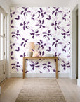 Falling Softly Plum botanical leaf wallpaper behind a console table in a light entry hallway