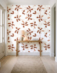 Falling Softly Terracotta botanical leaf wallpaper behind a console table in a light entry hallway