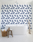 Gilded Frond Navy leaf wallpaper behind a freestanding tub in a bright coastal bathroom