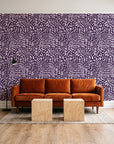 Grain Shift Aubergine minimalist dash wallpaper behind a rust velvet sofa in a bright coworking lounge