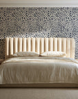 Grain Shift Oatmeal minimalist dash wallpaper behind a channel-tufted bed in a calm primary bedroom