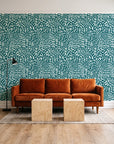 Grain Shift Teal minimalist dash wallpaper behind a rust velvet sofa in a bright coworking lounge