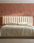 Grain Shift Terracotta minimalist dash wallpaper behind a channel-tufted bed in a calm primary bedroom