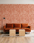Grain Shift Terracotta minimalist dash wallpaper behind a rust velvet sofa in a bright coworking lounge