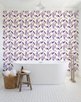 Hanging Garden Plum botanical wallpaper behind a freestanding tub in a bright coastal bathroom
