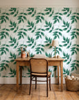Harvest Crown Emerald leafy branch wallpaper behind a vintage writing desk in a cozy craft-room home office