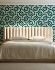 Indigo Labyrinth Emerald geometric wallpaper behind a channel-tufted bed in a calm primary bedroom