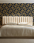 Indigo Labyrinth Midnight Gold geometric wallpaper behind a channel-tufted bed in a calm primary bedroom