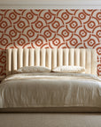 Indigo Labyrinth Terracotta geometric wallpaper behind a channel-tufted bed in a calm primary bedroom