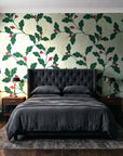 Ink & Oak Evergreen oak leaf and berry wallpaper behind a tufted headboard in a dark, moody bedroom