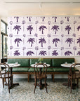 Ink & Shell Aubergine coastal palm and shell wallpaper above a green leather banquette in a sunlit neighborhood cafe