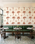 Ink & Shell Terracotta coastal palm and shell wallpaper above a green leather banquette in a sunlit neighborhood cafe