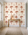 Ink & Shell Terracotta coastal palm and shell wallpaper behind a console table in a light entry hallway